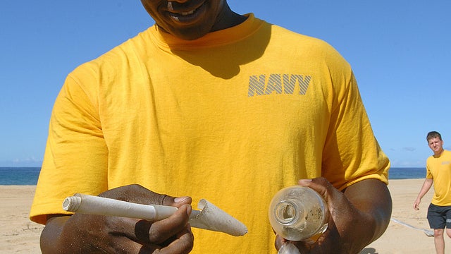 U.S. Navy Petty Officer Jon Moore removes a message from a bottle Sept. 15, 2011, apparently sent from an elementary school student in Kirishima, Japan, more than five years ago. The bottle was found during a beach cleanup at Pacific Missile Range Facilit 