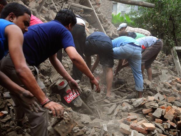 Nepalese people take out a motorbike buried 