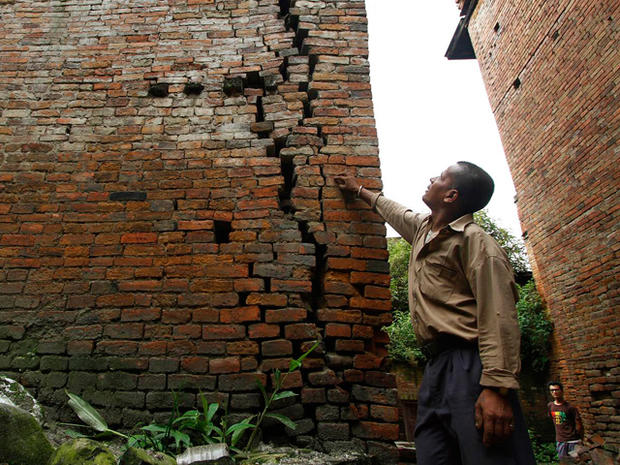 A man looks out a crack of a house damaged by an earthquake 