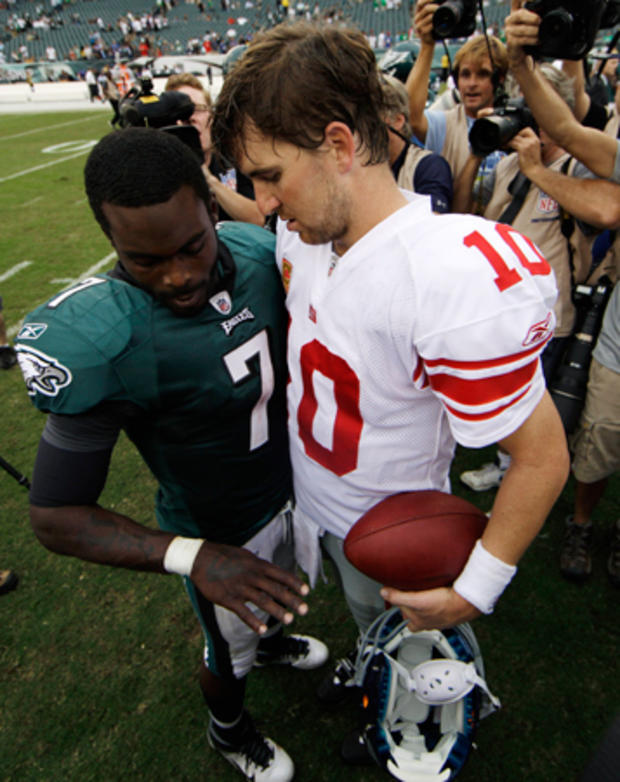 Michael Vick, left, shows his hand to Eli Manning 