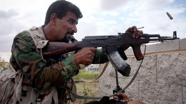 A revolutionary fighter fires at Gadhafi loyalist positions in Sirte, Libya, Thursday, Oct. 13, 2011. Anti-Gadhafi fighters have been closing in on armed supporters of the fugitive leader in Sirte, the most important of two major cities yet to be cleared  