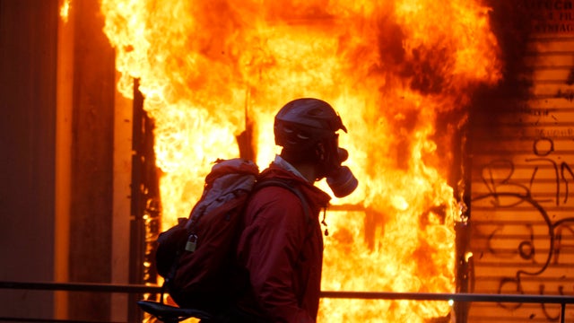A cyclist passes by a burning kiosk near the Finance Ministry during clashes in Athens Oct. 19, 2011. A two-day general strike that unions vow will be the largest in years grounded flights, disrupted public transport and shut down everything from shops to 