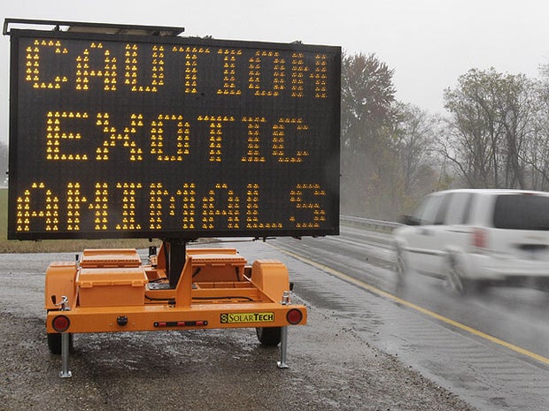 A sign warning motorists that exotic animals are on the loose rests on I-70, Oct. 19, 2011, near Zanesville, Ohio.  