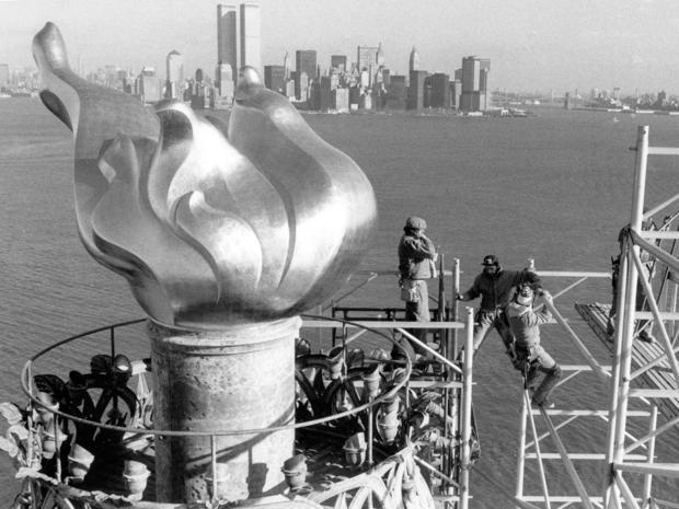 Workers remove scaffolding Dec. 17, 1985, from around the torch of the Statue of Liberty with the Manhattan skyline and the twin towers of the World Trade Center in the background. 