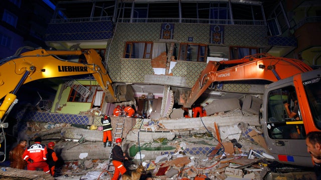 Rescuers work to excavate people believed to be trapped under a collapsed building in Ercis, eastern Turkey, late Monday 
