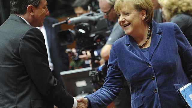 German Chancellor Angela Merkel, right, shakes hands with Slovenian Prime Minister Borut Pahor during a round table at an EU summit in Brussels on Oct. 26, 2011.  