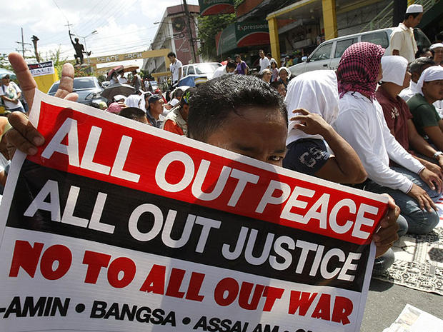 A Filipino Muslim flashes the peace sign as he holds a placard during a "Prayer-for-Peace" rally near the Presidential Palace Friday Oct. 28, 2011 in Manila, Philippines. 