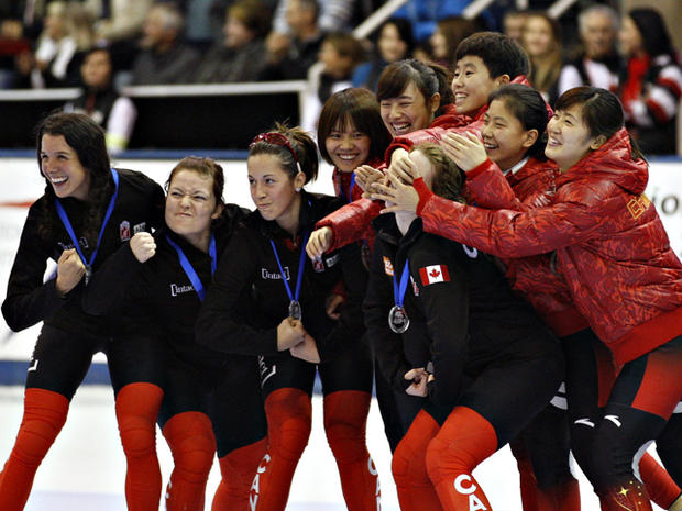 Marianne St. Gelais has her face hidden by the hands of the Chinese skaters 