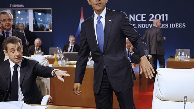 President Barack Obama takes his seat as he stands next to French President Nicolas Sarkozy during a working lunch at the G20 Summit in Cannes, France, Nov. 3, 2011.  