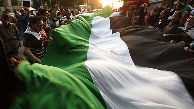 Protesters wave a big syrian flag during their anti-Syrian regime protest in front of the Arab league headquarters in Cairo, Egypt, Nov. 2, 2011.  