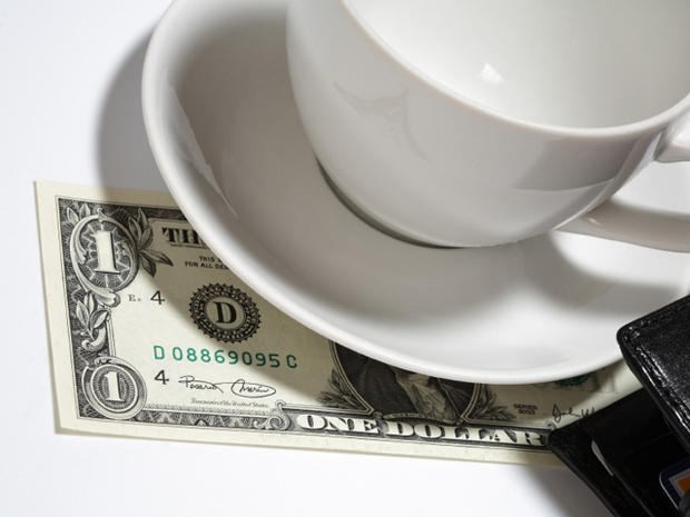 Closeup of one dollar, tea cup, saucer and wallet 