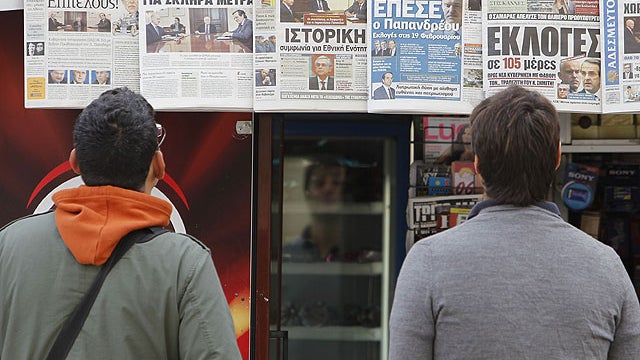 People read the front pages of the Greek daily newspapers at a kiosk in central Athens, Nov. 7, 2011 