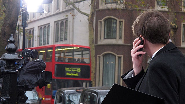 A television journalist speaks on the phone outside of London's Royal Courts of Justice on Nov. 14, 2011.  