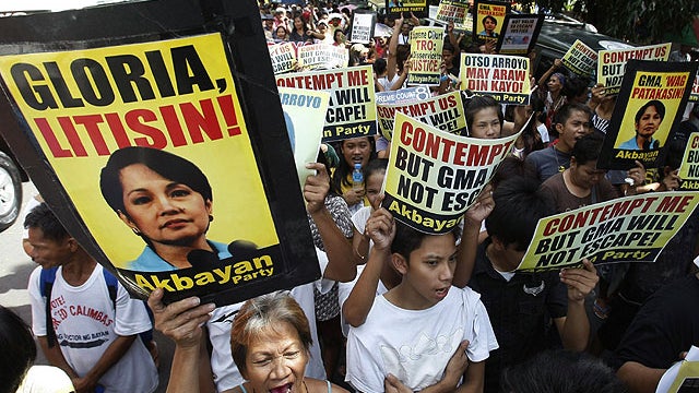 Hundreds of protesters shout slogans and display messages against former Philippine President Gloria Macapagal Arroyo as they march towards the Philippine Supreme Court in Manila, Nov. 18, 2011.  