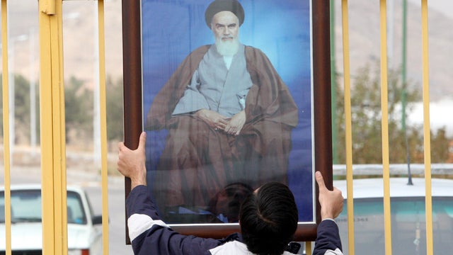 An Iranian student hangs a portrait of late revolutionary founder Ayatollah Khomeini on the gate of the Isfahan Uranium Conversion Facility during a gathering in support of Iran's nuclear program just outside the city of Isfahan, Iran, Nov. 15, 2011. 