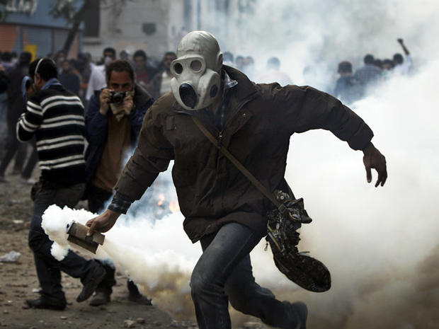 A protester throws a gas canister towards Egyptian riot police 