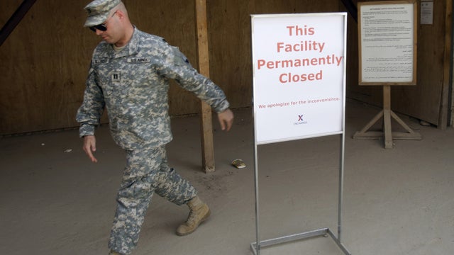 U.S. soldier walks past a sign outside a closed base at Camp Victory 