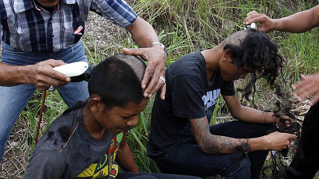 In this Tuesday, Dec. 13, 2011 photo, plain-clothed police officers shave the heads of punks at a police school compound in Aceh Besar, Aceh province, Indonesia.  