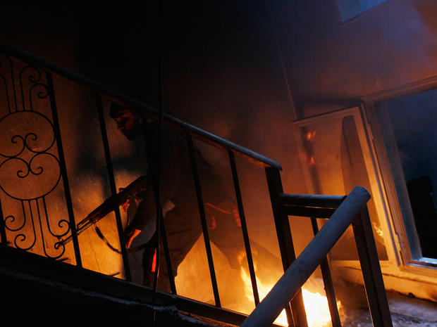 A libyan rebel fighter runs up a burning stairwell 