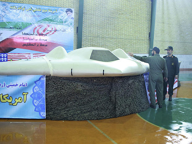 This photo released on Thursday, Dec. 8, 2011, by the Iranian Revolutionary Guards, claims to show US RQ-170 Sentinel drone which Tehran says its forces downed earlier this week, as the chief of the aerospace division of Iran's Revolutionary Guards, Gen. Amir Ali Hajizadeh, right, listens to an unidentified colonel, in an undisclosed location, Iran. 