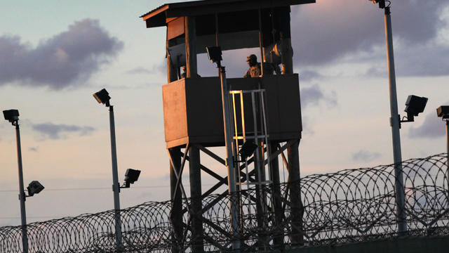 A U.S. military guard tower stands on the perimeter of a detainee camp  