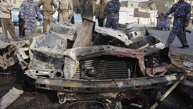 Iraqi security forces and people gather the scene of a car bomb attack in Baghdad, Iraq, Dec. 22, 2011.  