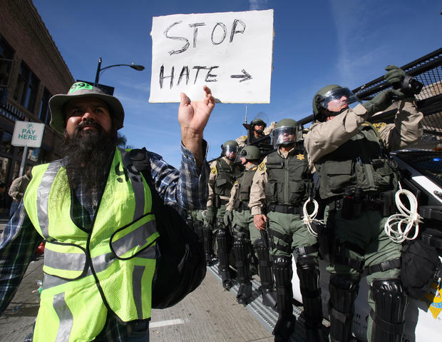 n Occupy protester with a sign marches in front of police officers along Colorado Boulevard during the 123rd Tournament of Roses Parade in Pasadena, Calif., Monday, Jan. 2, 2012. Several hundred Occupy protesters marched at the end of the Rose Parade in a 