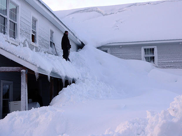 In this Saturday, Jan. 7, 2012 photo provided by the Alaska Division of Homeland Security and Emergency Management, a man stands on a house buried in snow in the fishing town of Cordova, Alaska. 
