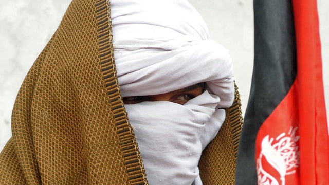 A Taliban fighter with his face covered looks on during a ceremony after joining Afghan government forces in Kandahar, Afghanistan, Dec. 20, 2011. 
