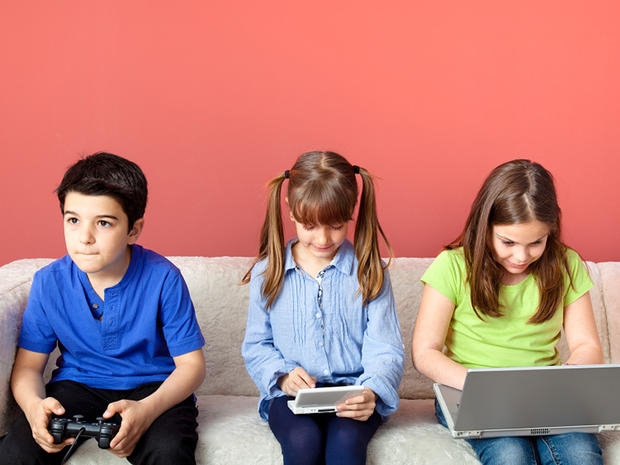Three children using video games and laptop. 
