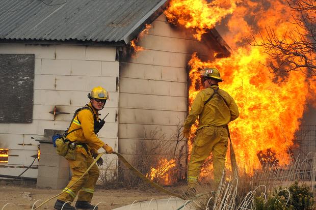 Firefighters wait for water before attacking an outbuilding adjacent to a home 