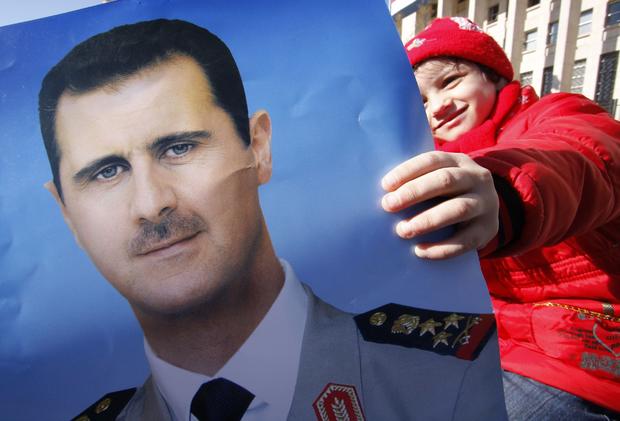 Pro-Syrian regime protester holds a portrait of Syrian President Bashar Assad 