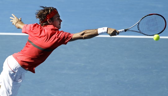Roger Federer makes a backhand return 