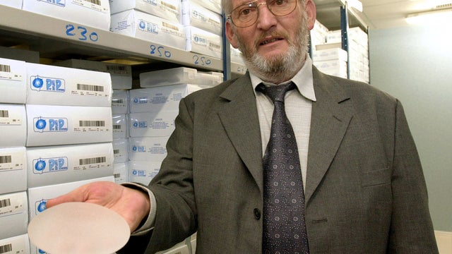 Former PIP President Jean-Claude Mas holds a breast implant 