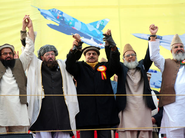 Pakistani Islamist and political party leaders, from left to right Hafiz Muhammad Saeed, Maulana Sami ul Haq, Hamid Gul, Syed Munawar Hasan and Muhammad Ahmed Ludhianvi, raise hands in solidarity at a Pakistan Defense Council rally in Rawalpindi, Pakistan, Jan. 22, 2012. 