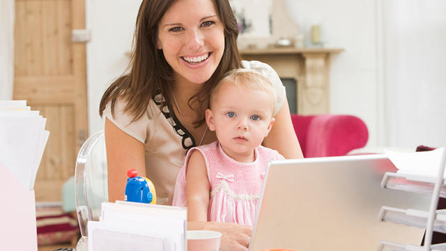 Mother and baby in home office with laptop 