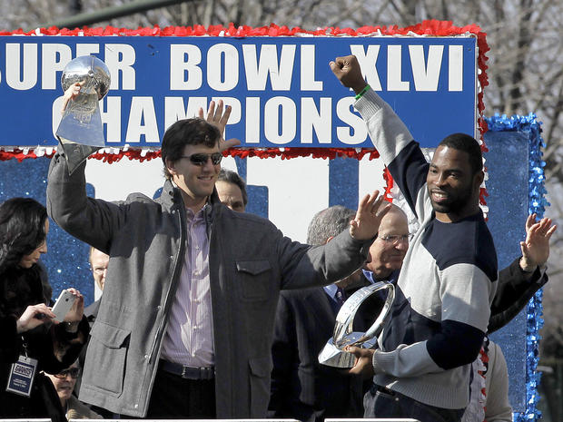 Eli Manning, center, holding the Vince Lombardi Trophy and defensive end Justin Tuck 