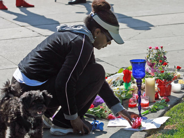 A fan places a flower at a memorial outside the Beverly Hills Hilton Hotel on Feb. 12, 2012 