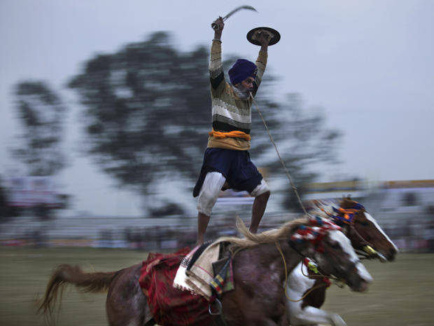 Sikh riding on two horses, performs during a rural sports festival 