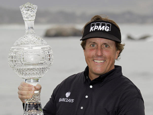 Phil Mickelson holds his trophy on the 18th green of the Pebble Beach Golf 