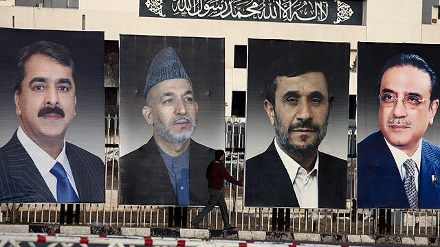 A man walks past pictures of, from left, Pakistan's Prime Minister Yousaf Raza Gilani, Afghan President Hamid Karzai, Iranian President Mahmoud Ahmedinejad and Pakistan's President Asif Ali Zardari, displayed outside the Parliament in Islamabad, Pakistan  