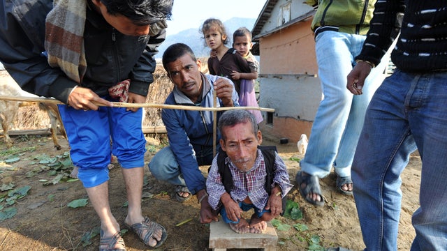 72-year-old Chandra Bahadur Dangi looks on as villagers measures him near his home in Reemkholi village, Dang district, some 540 kilometers southwest of Kathmandu on Feb. 9, 2012.  