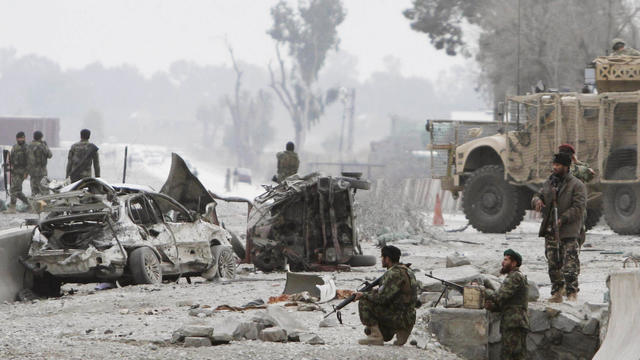 Afghan soldiers are on alert at the scene of a suicide attack at the gate of an airport in Jalalabad 