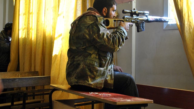 A Syrian rebel aims his rifle inside a classroom at a school in the Deir Baalbeh neighborhood in Homs, Syria, Feb. 22, 2012. 