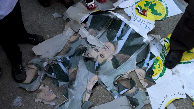 Protesters stand among damaged portraits of Hafez Al-Assad, former president of Syria and the father of current president Bashar Al-Assad, during anti-government protest in town in north Syria Friday 