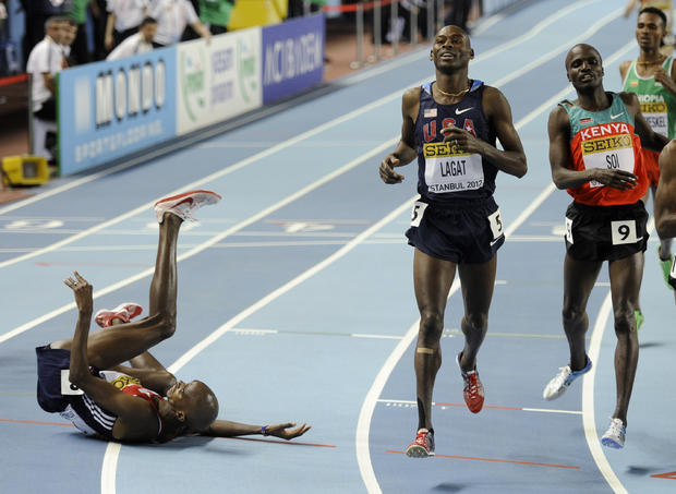 Britain's Mo Farah falls after crossing the line as United States' Bernard Lagat, center, wins the gold in the Men's 3000m race 