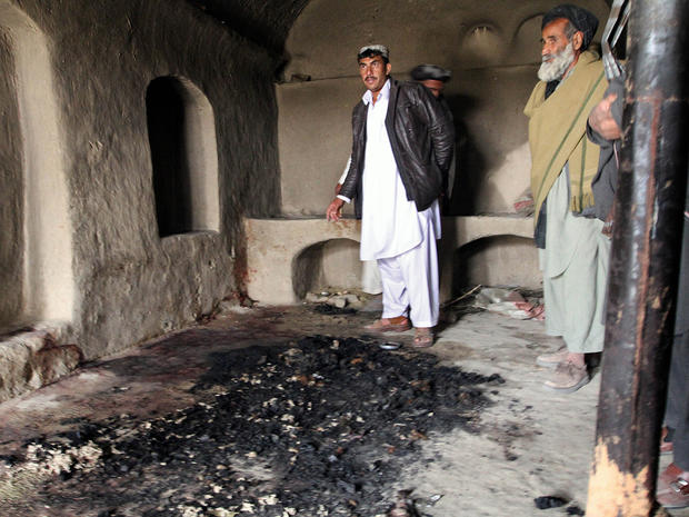 Men stand next to blood stains and charred remains inside a home where witnesses say Afghans were killed by a U.S. soldier 
