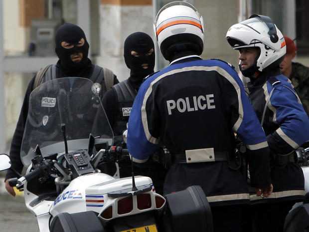 French police officers and a soldier stand close to the apartment building where a suspect in the shooting at the Ozar Hatorah Jewish school was barricaded in Toulouse, France, March 21, 2012. 