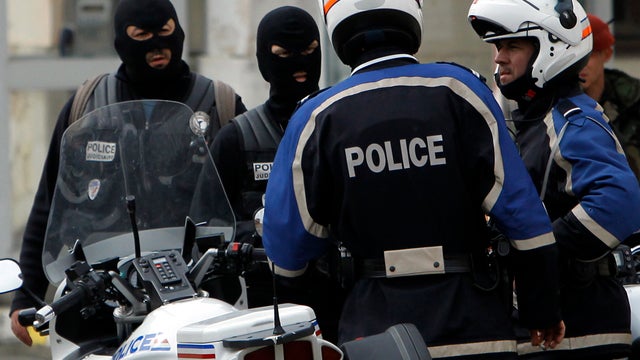 French police officers and a soldier stand close to the apartment building where a suspect in the shooting at the Ozar Hatorah Jewish school was barricaded in Toulouse, France, March 21, 2012. 