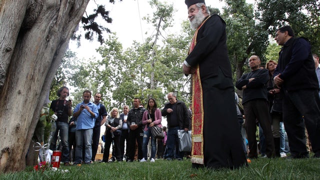 A Greek Orthodox priest holds a memorial service at the site where an elderly man shot himself at Athens' main Syntagma square, on April 4, 2012.  